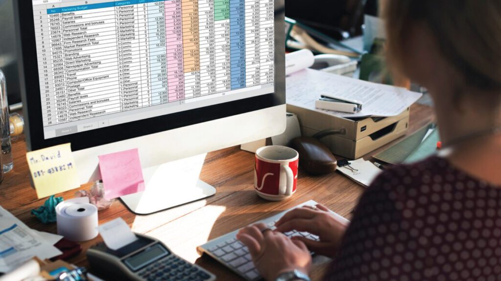 Offshoring - Accountant working with calculator and spreadsheets. - iSupportWorldwide